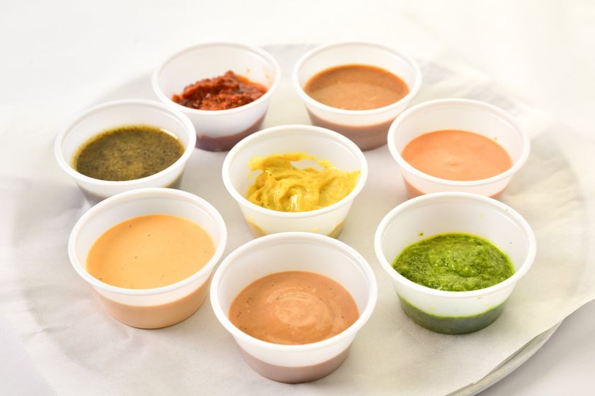 Assorted house-made sauces in small cups: chipotle mayo, pesto, mustard, spicy ranch, and more