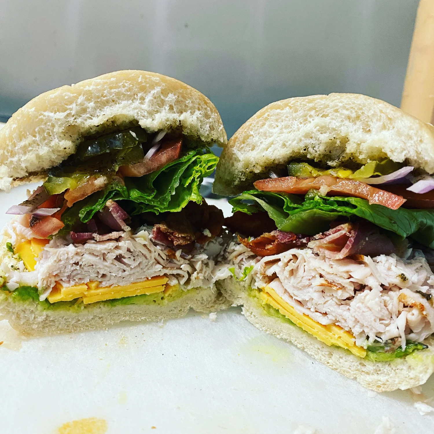 Turkey bacon club sandwich, sliced in half, on a fresh roll with lettuce, tomato, and cheddar